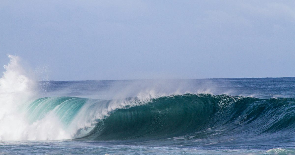 A clean line of swell breaking under grey skies