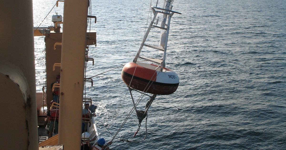 A weather and wave buoy being lowered into the sea from a NOAA ship